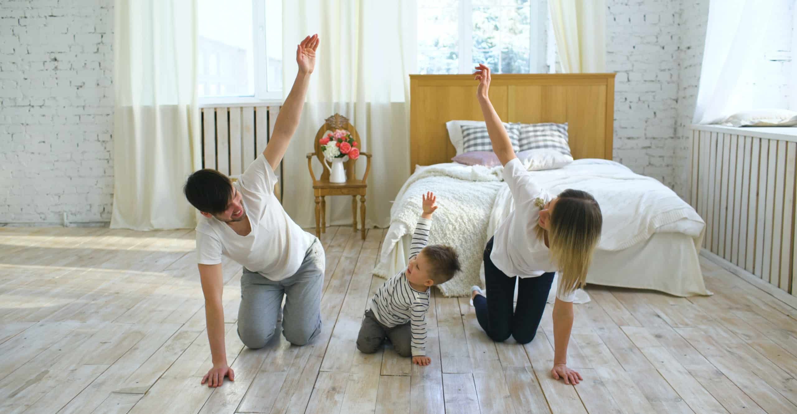Family doing gymnastic exercises in bedroom at home – healthy life education