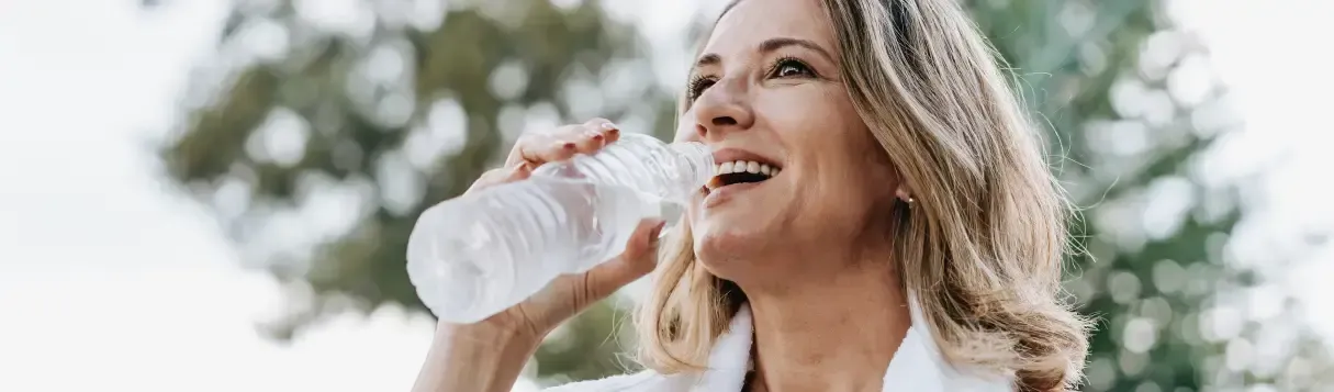 woman drinking from a water bottle after a workout outside