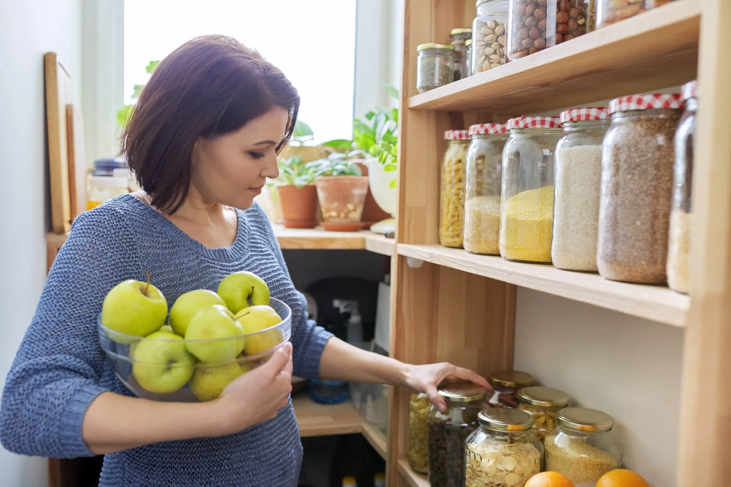 Woman,With,Bowl,Of,Green,Apples,In,Pantry,,Organizing,In