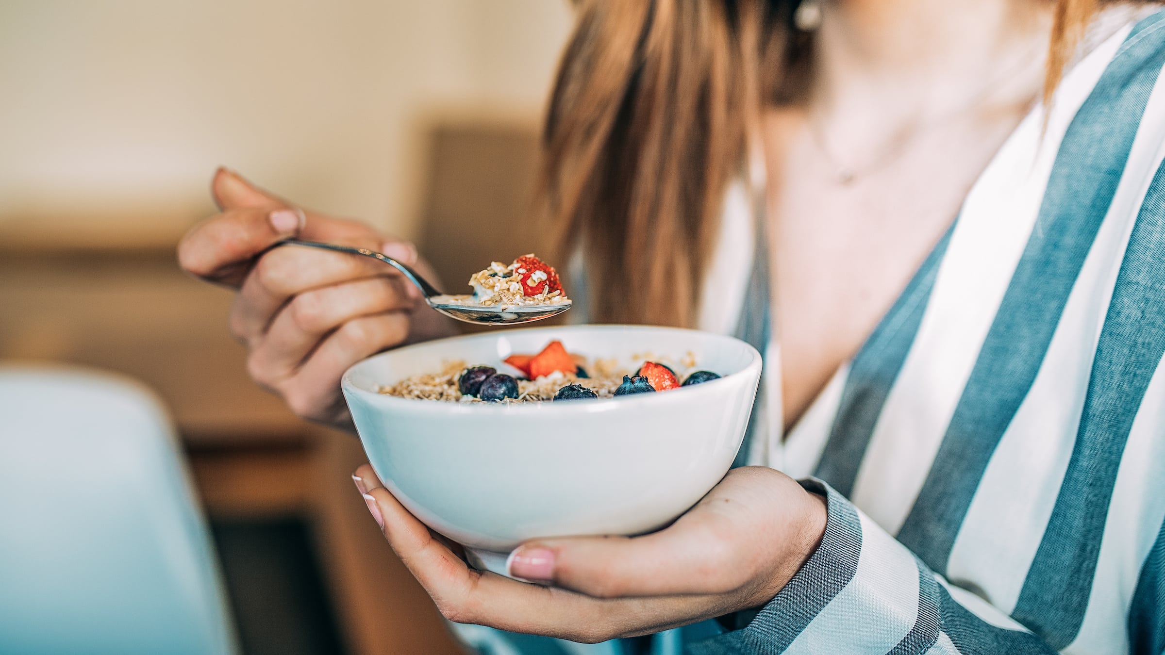 Woman holding bowl of cereal with blueberries and strawberries